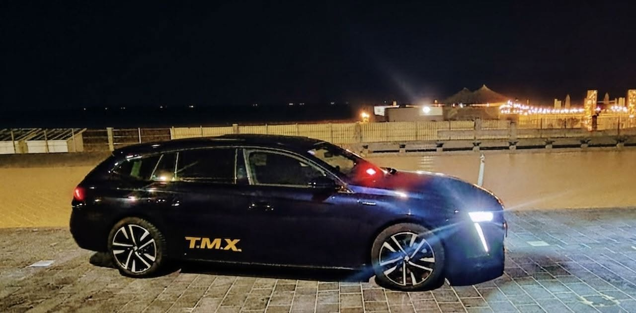 Taxi T.M.X. bij nacht aan de kustpromenade